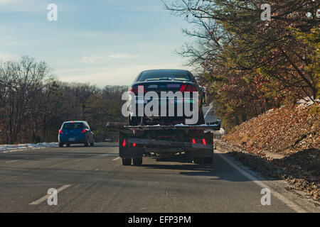 Auto auf Rückseite Flachbett Abschleppwagen unterwegs - USA Stockfoto