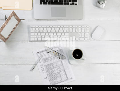 Ansicht von oben Winkel des Büro-Desktop bestehend aus Laptop, Tastatur, Stifte, Maus, Bilderrahmen, Telefon, Kaffee, Lesebrille, Steuer Stockfoto