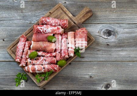 Ansicht von oben horizontal Bild der verschiedenen Fleischsorten auf dem Board mit Schinken, Schweinefleisch, Rindfleisch, Petersilie und Oliven auf rustikalen Holz. Stockfoto