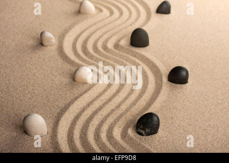 Linie, die schwarzen und weißen Steinen, stehend auf dem Sand, können als Hintergrund verwendet werden Stockfoto