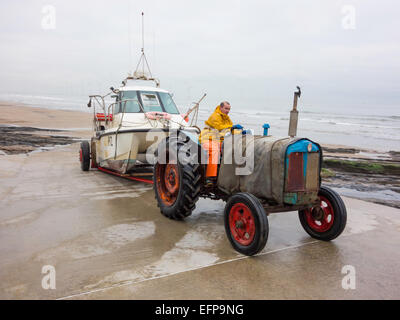 Fischer fahren einen Traktor schleppen sein Boot auf der Helling vom Strand Redcar Cleveland UK Stockfoto