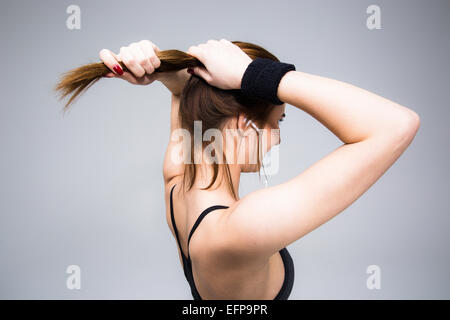 Seite Ansicht Porträt einer Frau hält ihr Haar auf grauem Hintergrund Stockfoto