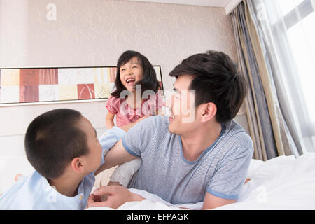 Vater und die Kinder spielen im Bett Stockfoto