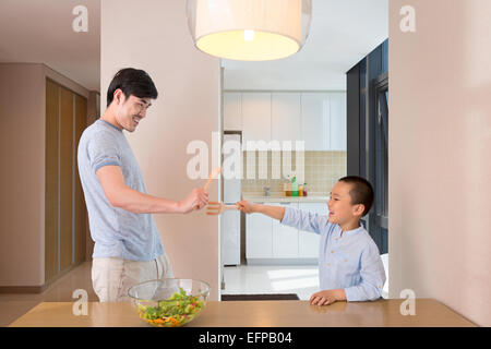 Vater und Sohn Fechten in Küche Stockfoto