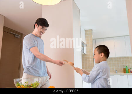 Vater und Sohn Fechten in Küche Stockfoto