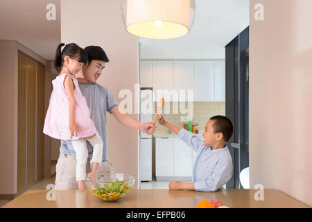 Vater und Kinder fechten in Küche Stockfoto