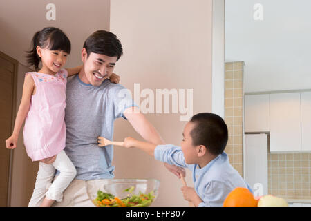 Vater und Kinder fechten in Küche Stockfoto