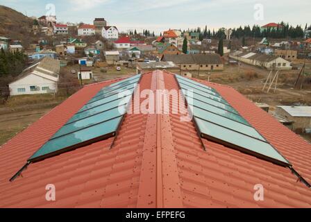 Heisses Wasser mit Sonnenenergie (Geliosystem) auf dem roten Hausdach. Stockfoto