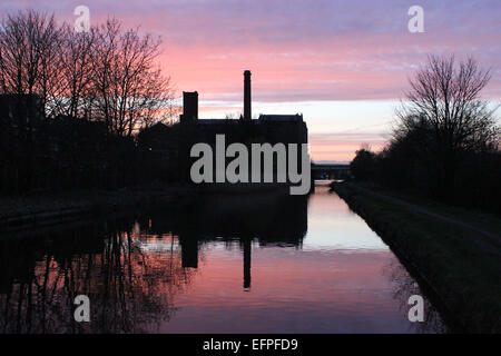 Burscough Mühle ist Silhouette und spiegelt sich in The Leeds und Liverpool Canal in der Abenddämmerung. Stockfoto