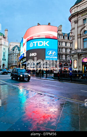 London, Vereinigtes Königreich - 12. April 2013: berühmten Piccadilly Circus Neon Schilder spiegelt sich auf der Straße mit dem Taxi in London, UK Stockfoto