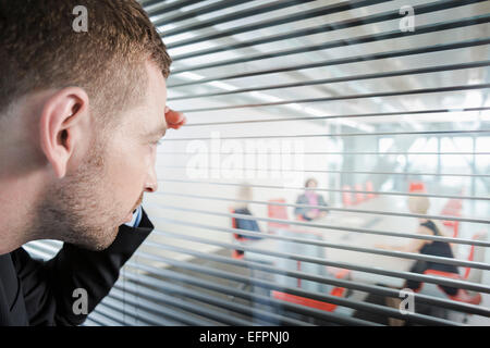 Mann spähte durch Fenster-Vorhänge Stockfoto