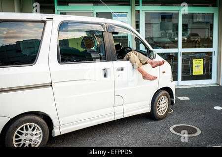 Ein Mann nimmt ein Nickerchen in seinem Auto. Stockfoto