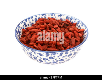 Roten Goji-Beeren in einer blau-weißen Porzellanschüssel mit floralem Design, isoliert auf weißem Hintergrund Stockfoto