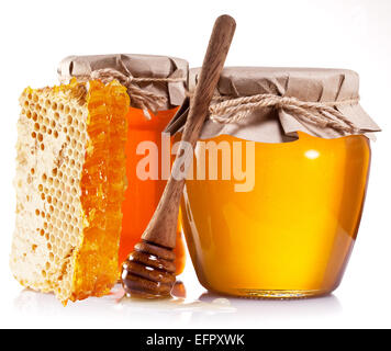 Glas-Dosen voller Honig, Waben und Holzstab auf weißem Hintergrund. Stockfoto