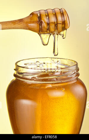 Honig-Tröpfchen aus Holzstab auf gelbem Hintergrund. Stockfoto
