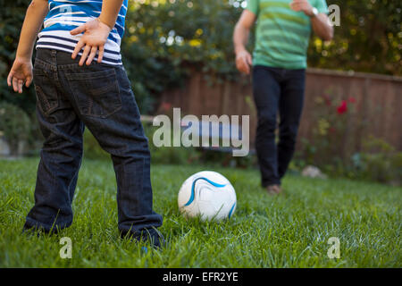 Vater und Sohn im Garten Fußball spielen Stockfoto