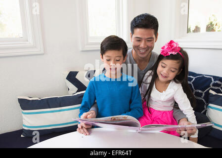 Reifer Mann lesen Märchenbuch, Sohn und Tochter auf sofa Stockfoto