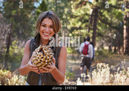 Porträt der jungen Frau im Wald mit großer Tannenzapfen, Los Angeles, Kalifornien, USA Stockfoto