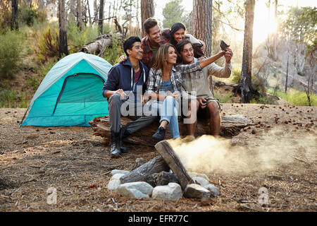Vier junge Erwachsene Freunde unter Smartphone Selfie Lagerfeuer im Wald, Los Angeles, Kalifornien, USA Stockfoto