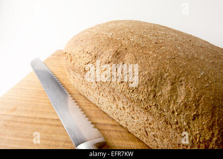 Frisch gebackene Vollkorn Brot auf einem hölzernen Brot-Brett mit Brotmesser Stockfoto