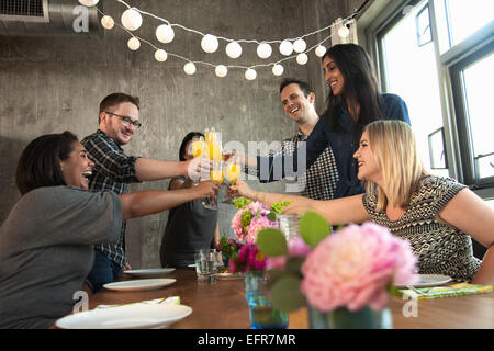 Gruppe von Freunden an Tisch, Brille, anheben, Toast machen Stockfoto