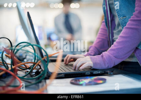 Eine Person mit einem Laptopcomputer. Scheibe und Drähte an der Theke. -Werkstatt. Stockfoto