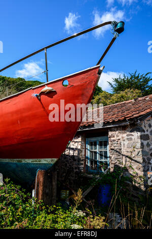 Altes rotes Boot stehend hoch und trocken in einem Cottage Garten, Porlock, Somerset. Stockfoto