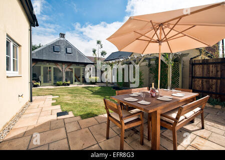 Der Garten hinter dem Haus & Terrasse eine moderne britische Haus mit Gartenmöbeln, garage & trennen Büro in Wiltshire, Großbritannien Stockfoto