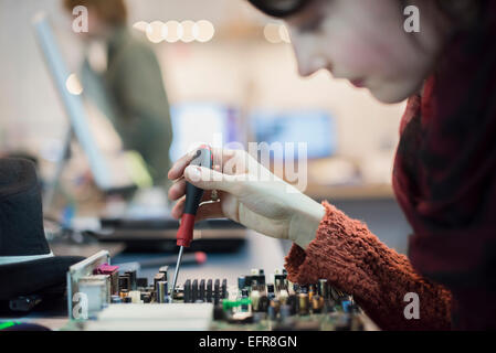 Computer-Werkstatt. Eine Frau mit einer elektronischen Schraubendreher-Tool auf einem Computer-Platine. Stockfoto