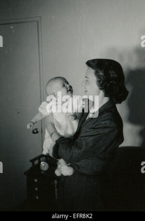 Kanada. 12. Dezember 2014. CA. 1950er Jahre: Reproduktion einer antiken Foto zeigt Frau Pflege eines Babys in ihr Arme © Igor Golovniov/ZUMA Wire/ZUMAPRESS.com/Alamy Live-Nachrichten Stockfoto