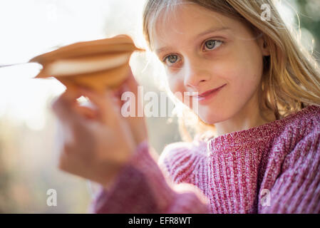 Blonde Mädchen stehen in einem Wald im Herbst, hochhalten und mit Blick auf ein Papier Vogel. Stockfoto