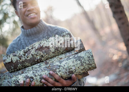 Mann mit Brennholz im Wald im Herbst. Stockfoto