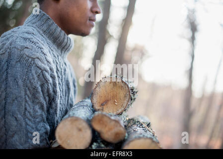 Mann mit Brennholz im Wald im Herbst. Stockfoto