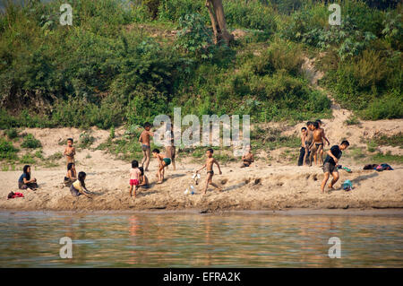 Horizontale Ansicht von einer Gruppe von Kindern spielen und entspannen an den Ufern des Mekong-Flusses. Stockfoto