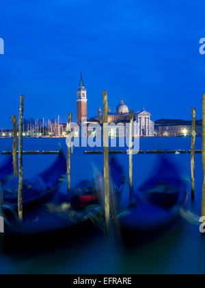 Riva Degli Schiavoni und der Piazza San Marco Island und die Kirche von San Giorgio Maggiore. Gondeln vor Anker in der Abenddämmerung. Stockfoto