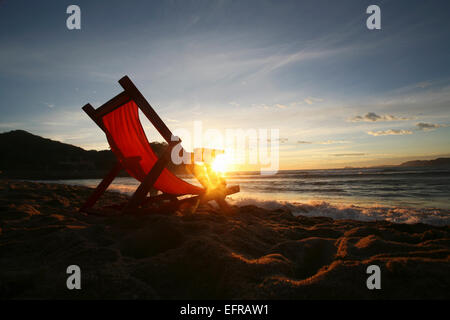 Ein Stuhl auf dem Sand, mit Blick auf das Wasser. Stockfoto