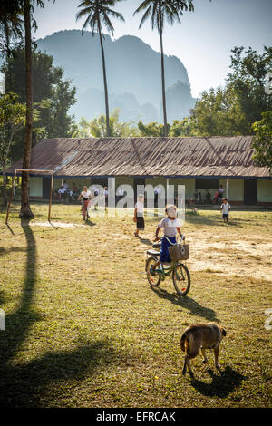 Schülerinnen und Schüler Reiten eines Fahrrades, Vang Vieng, Laos. Stockfoto