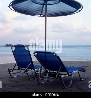 Zwei am Strand liegen und Sonnenschirm am Strand an einem Vormittag Stockfoto