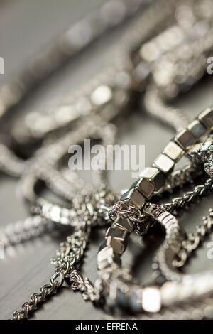 Verschiedene Silber Modeschmuck mit einem Durcheinander Haufen Ketten mit verschiedenen geformten Links, einem klaren Kristallperle und eine Halskette Stockfoto