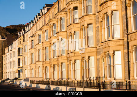 Reihenhäuser entlang der Victoria Terrasse, mit Blick auf Strand und Cardigan Bay bei Sonnenuntergang, Ceredigion, Mid Wales, Aberystwyth, Wales. Stockfoto