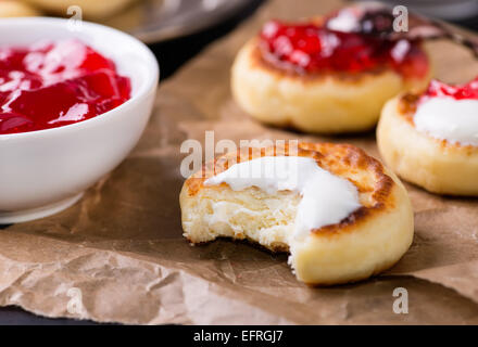 Quark Pfannkuchen mit saurer Sahne und Johannisbeeren Marmelade, Closeup, selektiven Fokus Stockfoto