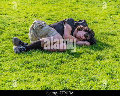 Ein junger Obdachloser schläft liegen außen auf dem grünen Rasen vor dem Rathaus in Santa Barbara, Kalifornien. Stockfoto