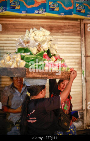 Eine Frau mit Nahrungsmitteln auf dem Kopf in Bali, Indonesien Stockfoto