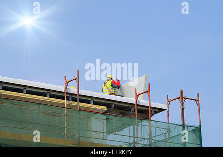 Mann arbeitet auf dem neuen Dach an einem sonnigen Tag Stockfoto