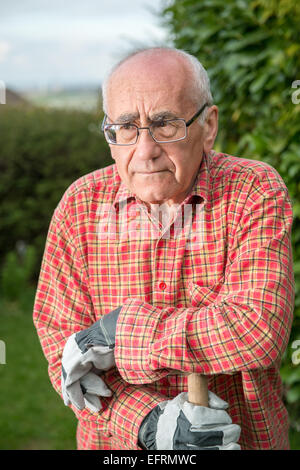 Ältere Mann in Garten, Tragen von Kleidung und halten Spaten Stockfoto