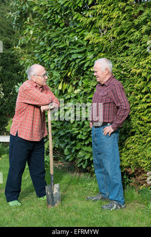 zwei ältere Männer stehen im Garten und Descussing, hält einen Spaten Stockfoto