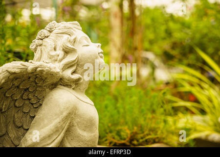 glücklich und lächelnd kleine Engel Skulptur im Garten Stockfoto