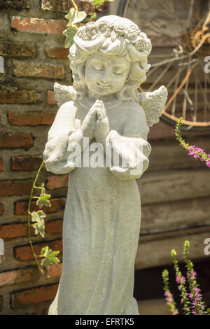 beten und lächelnd kleine Engel Skulptur im Garten Stockfoto