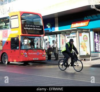 Ein Nottingham City Transportbus holt Passagiere, England UK ein Radfahrer vorbei Stockfoto