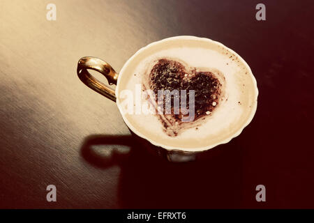 Tasse Kaffee mit Schokolade Herzform auf Milchschaum. Romantische Morgenlicht. Jahrgang Stockfoto